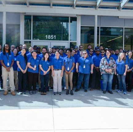 Photo: a group of individuals in blue shirts standing in front of a building