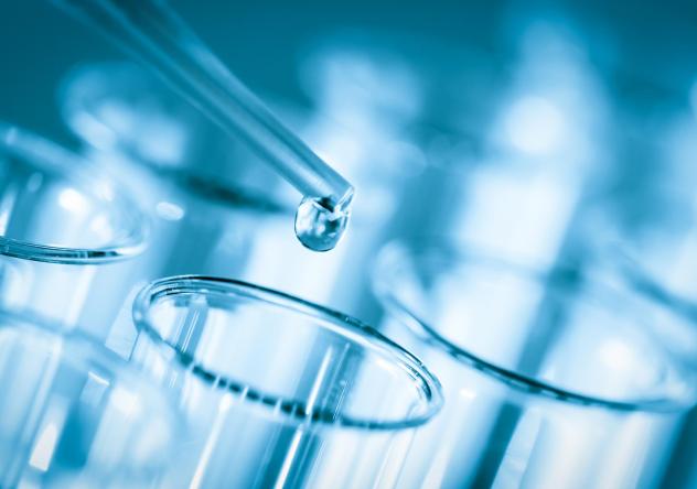 Photo: a pipette dripping clear liquid into a series of glass test tubes