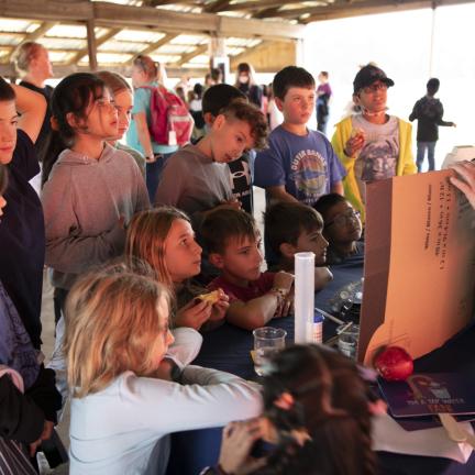 Photo: A group of children watching a presentation at a table.