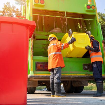 Photo: garbage men lifting a bin into a garbage truck.