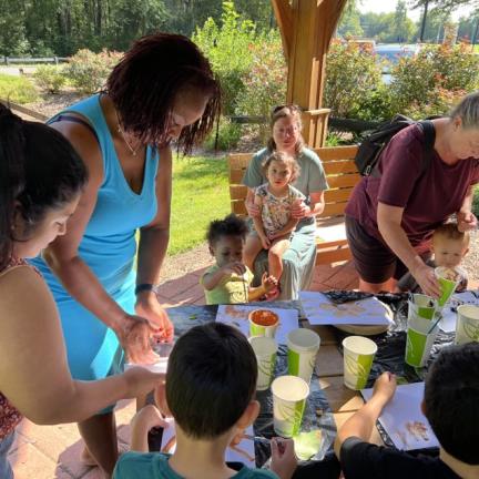 Photo: a group of adults and kids performing a science activity at a table