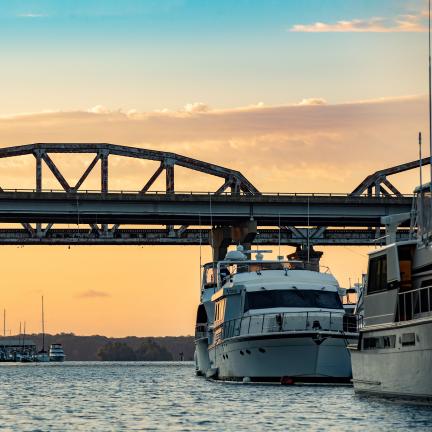 Two Boats under a Bridge at Sunset 