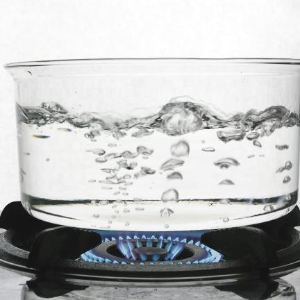 Photo: boiling water in a glass pot on a stove