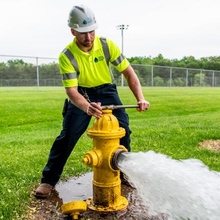 Photo: a man in safety gear flushing a hydrant