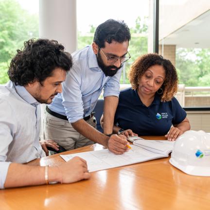 Photo: three individuals looking at documents at a conference table