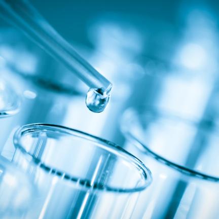 Photo: a pipette dripping clear liquid into a series of glass test tubes