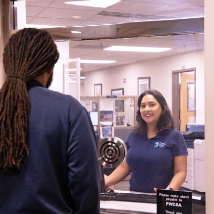 A customer service representative assists a customer at a window