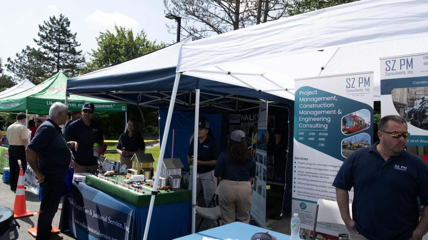 Photo: individuals interact at a booth at a vendor fair.