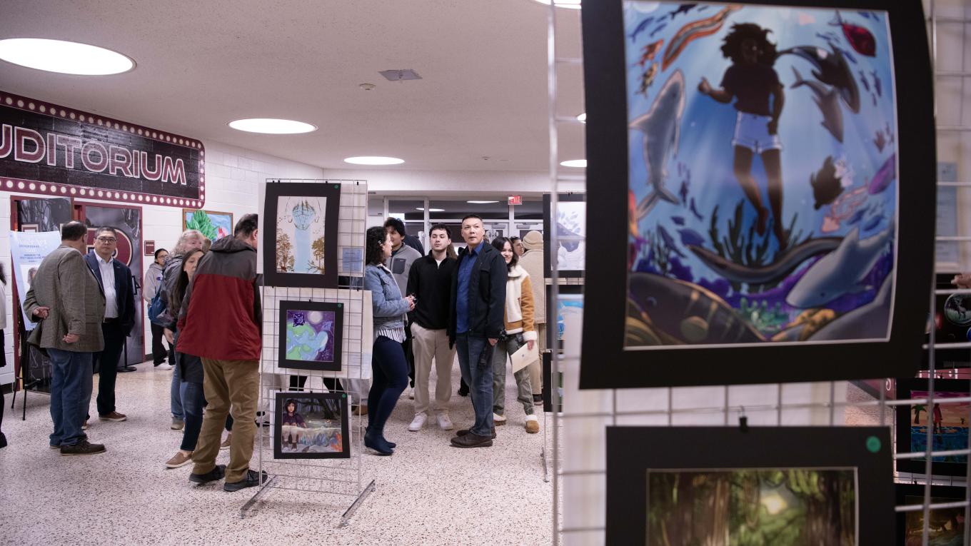 Individuals viewing art in a gallery held in a high school lobby