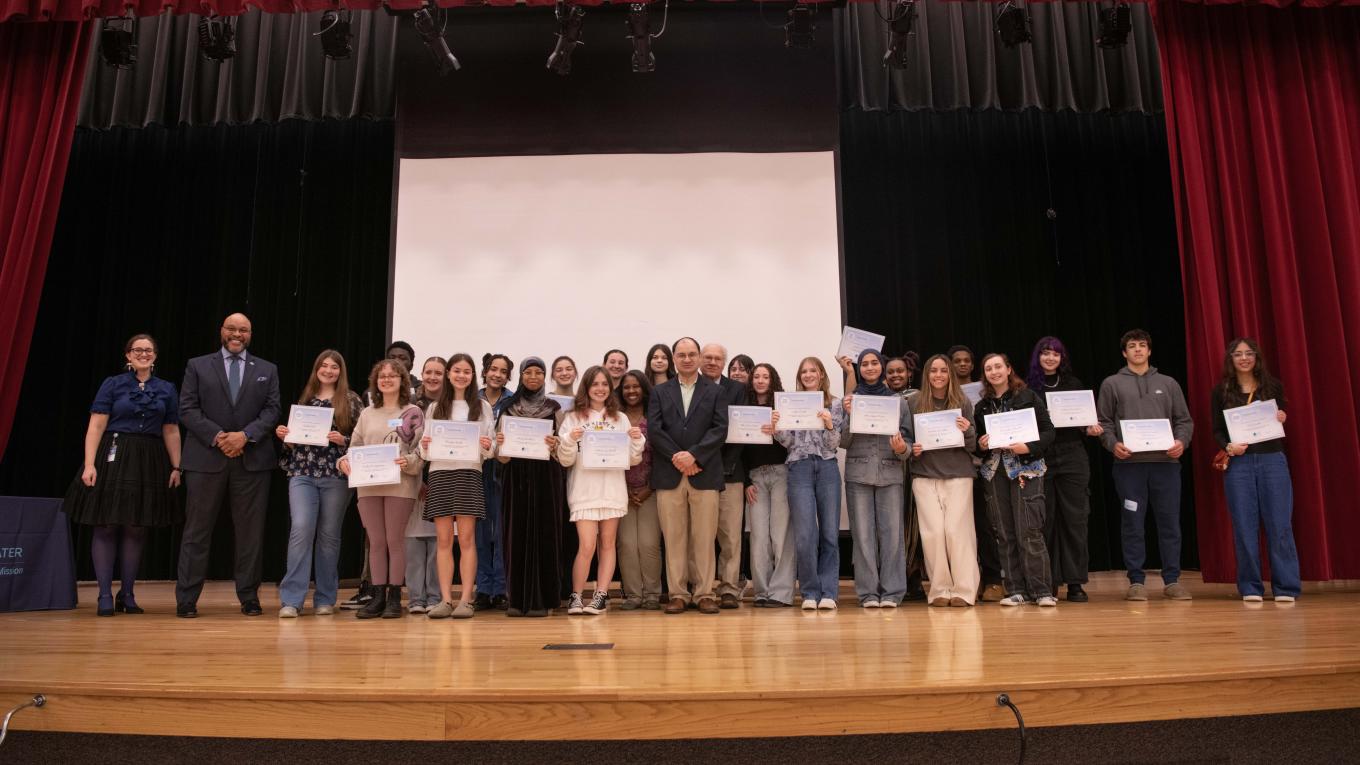 A group of approximately 30 individuals on a stage. Many are holding certificates.