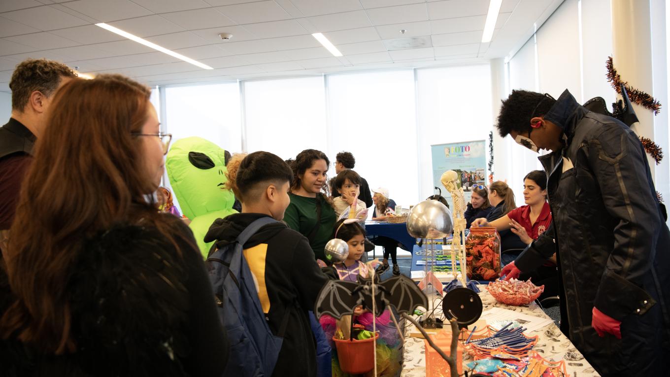 Individuals line up at tables at a Halloween-themed event