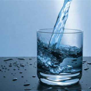 Water pouring into a glass with a blue background