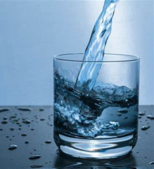 Water pouring into a glass with a blue background