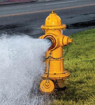 A yellow fire hydrant open with water rushing out