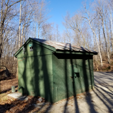 Photo: a small building made of green painted bricks in the woods