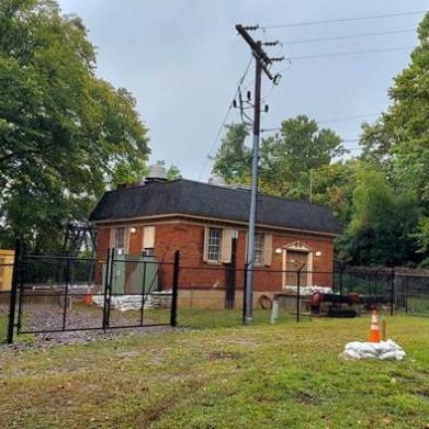 A small brick building surrounded by chain link fence