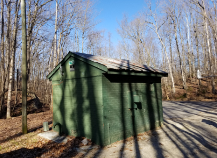 Photo: a small building made of green painted bricks in the woods