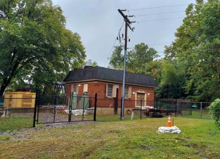 A small brick building surrounded by chain link fence