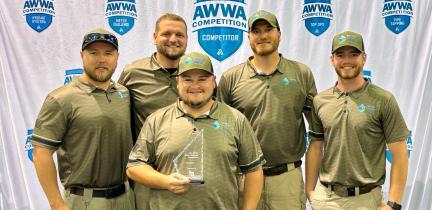 Photo: Five men wearing matching polos and hats accept an award