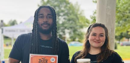 Photo: two community outreach staff holding items at a community fair