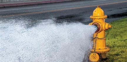 A yellow fire hydrant open with water rushing out