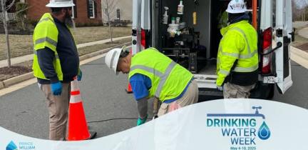 Individuals work to scope a sewer manhole outside of a large work truck