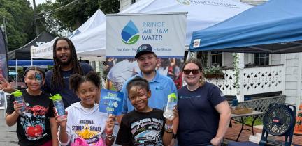 A group of individuals stands in front of a tented booth at a public event