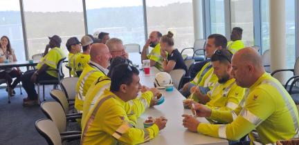 People in bright yellow work shirts gathered around a table eating ice cream
