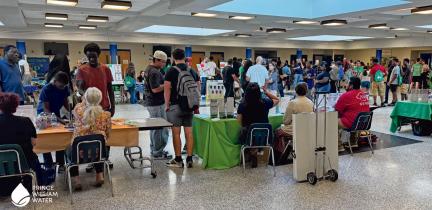 Individuals visit tables at a fair held in a high school lobby