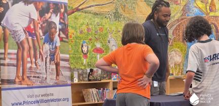 Two children visit a table with an educational display in a library.