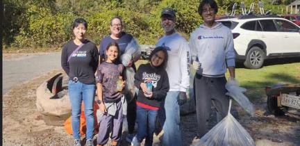 A group of individuals holding full trash bags for a community cleanup on a sunny day.