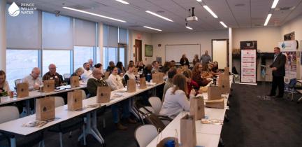A group of adults sitting attentively in rows at tables watching a presentation