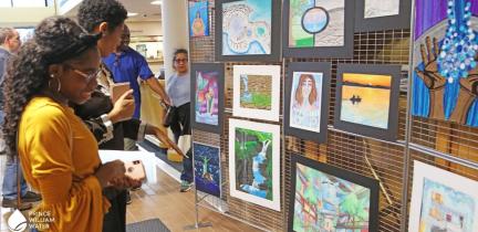 Individuals looking at artwork entries in a gallery
