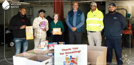 A group of individuals standing in front of boxes of food with a sign that says "Thank you for donating!"