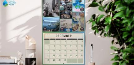 A calendar showcasing Water Art Invitational artwork is displayed on the wall