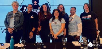 A group of women standing in front of a presentation screen at a conference