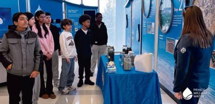 A group of children learning at a display table in an education center