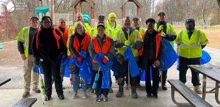 A group of individuals at a trash cleanup holding empty blue trash bags