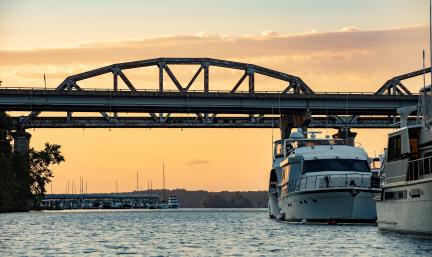 Two Boats under a Bridge at Sunset 