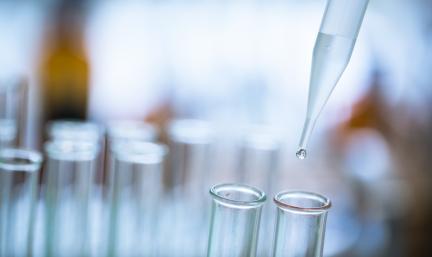 Photo: a dropper dropping a clear liquid into a test tube