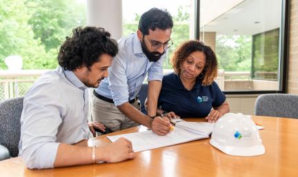 Photo: three individuals looking at documents at a conference table