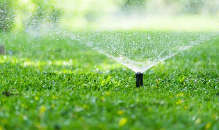Photo: an automatic sprinkler irrigating grass