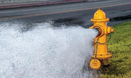 A yellow fire hydrant open with water rushing out