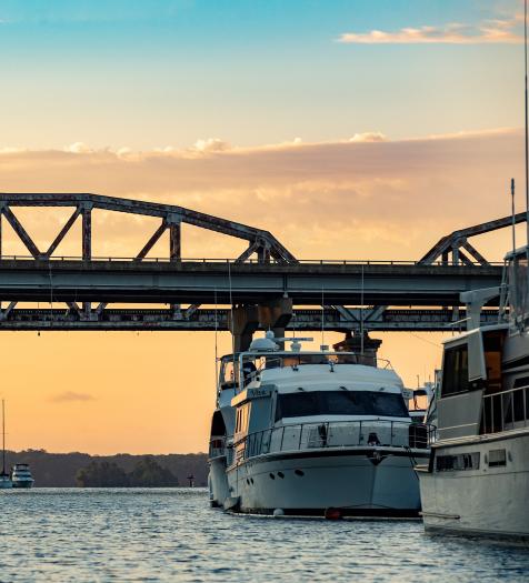 Two Boats under a Bridge at Sunset 