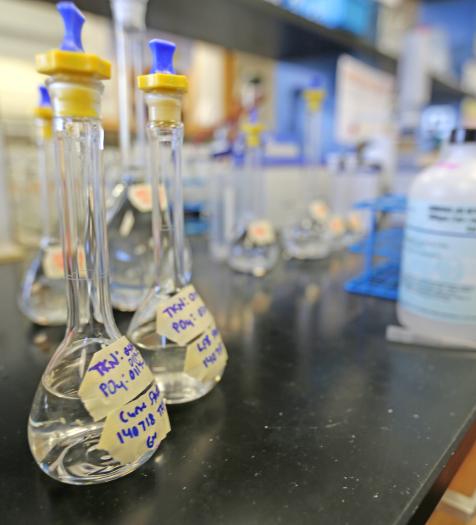 Photo: glass vials containing a clear liquid on a laboratory workbench