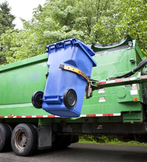 Photo: a garbage truck picking up and emptying a garbage can