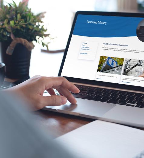 A hand resting on a laptop that has a webpage called "Reading Library" pulled up on it.