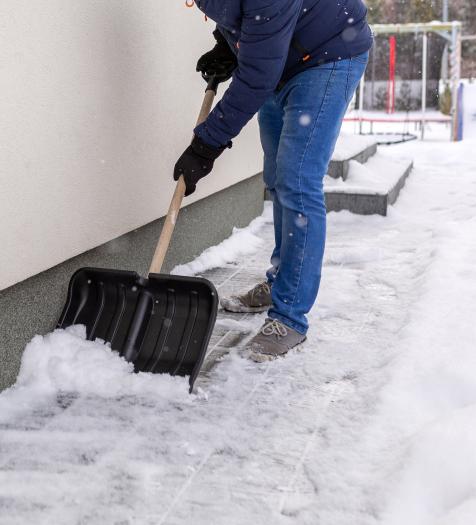 A person shoveling snow on a cement walkway