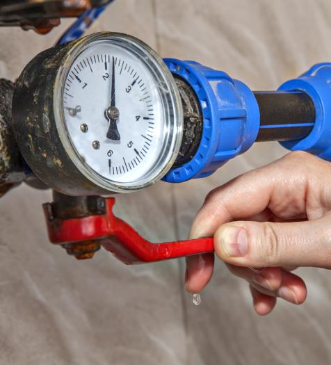 A hand turning off a water shut off