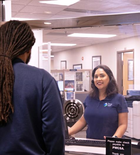 A customer service representative assists a customer at a window